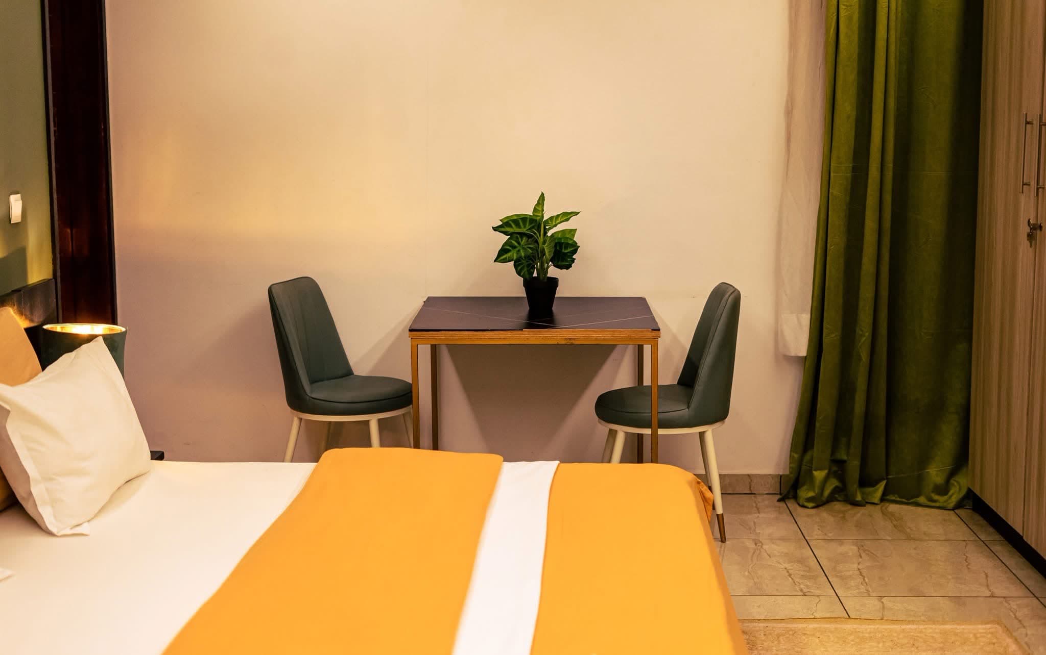 Coin travail d’une chambre avec table élégante, deux chaises et plante verte