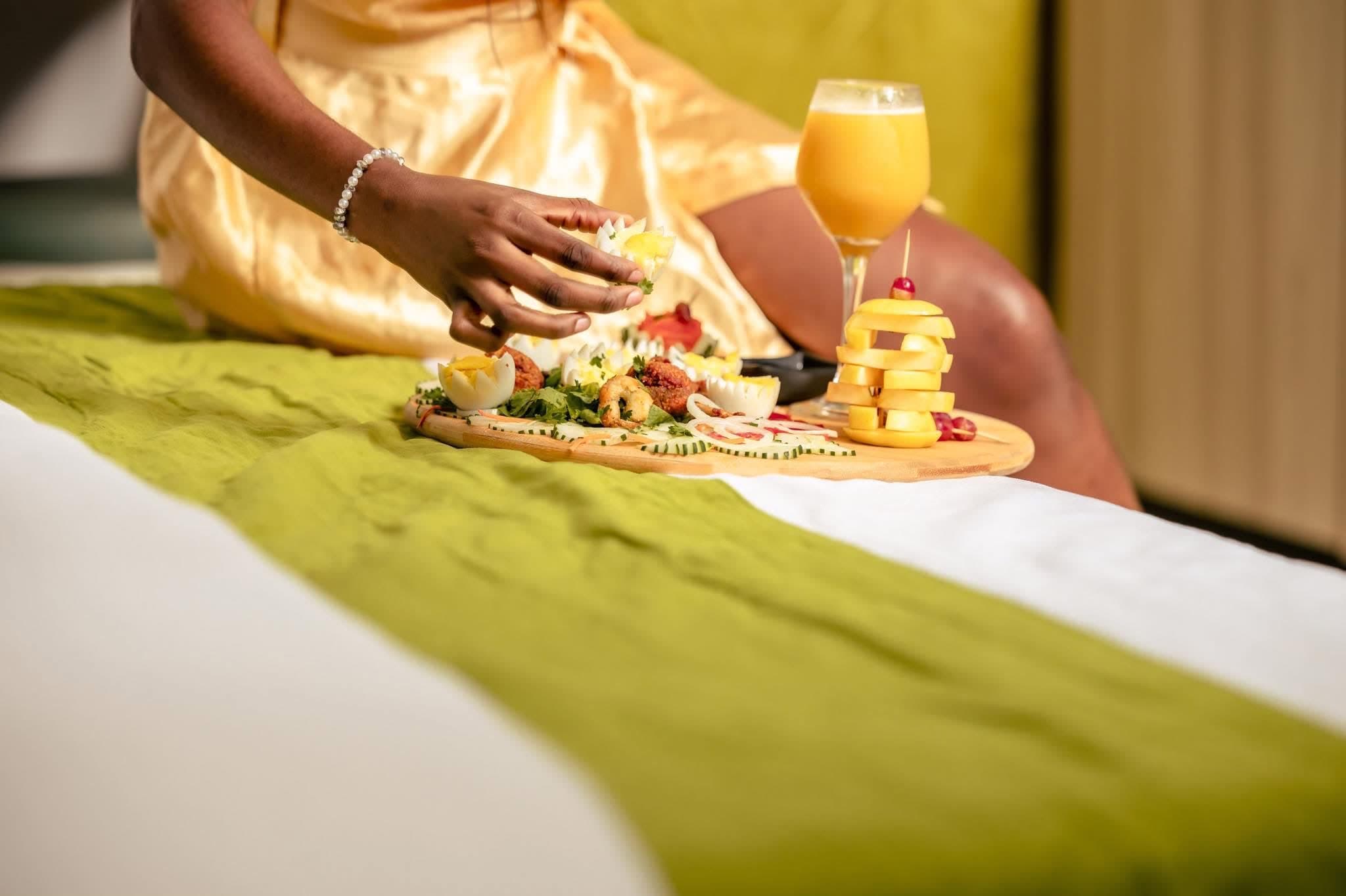Cliente savourant son petit-déjeuner au lit dans une chambre de NH Le Rêve à Grand-Bassam