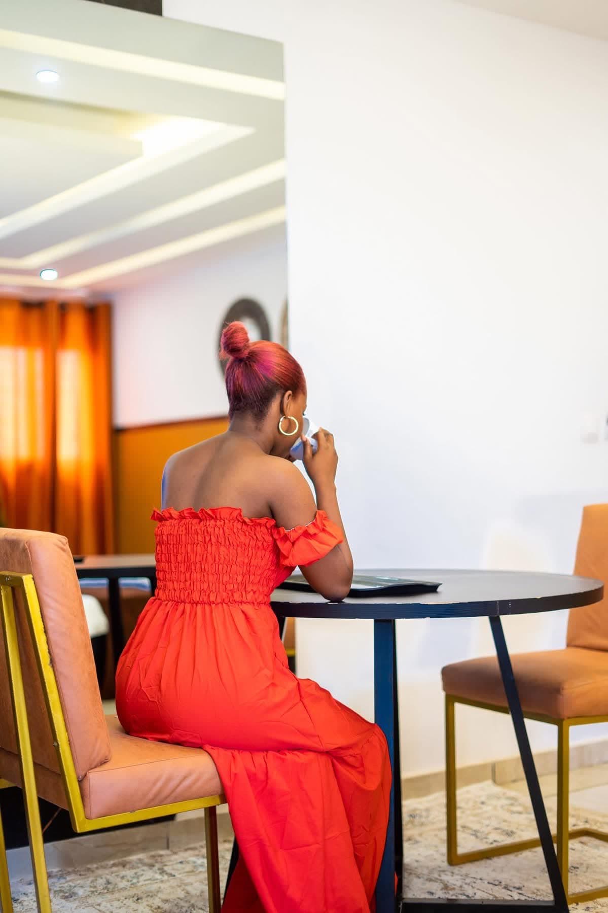 Cliente en robe rouge savourant un café au salon